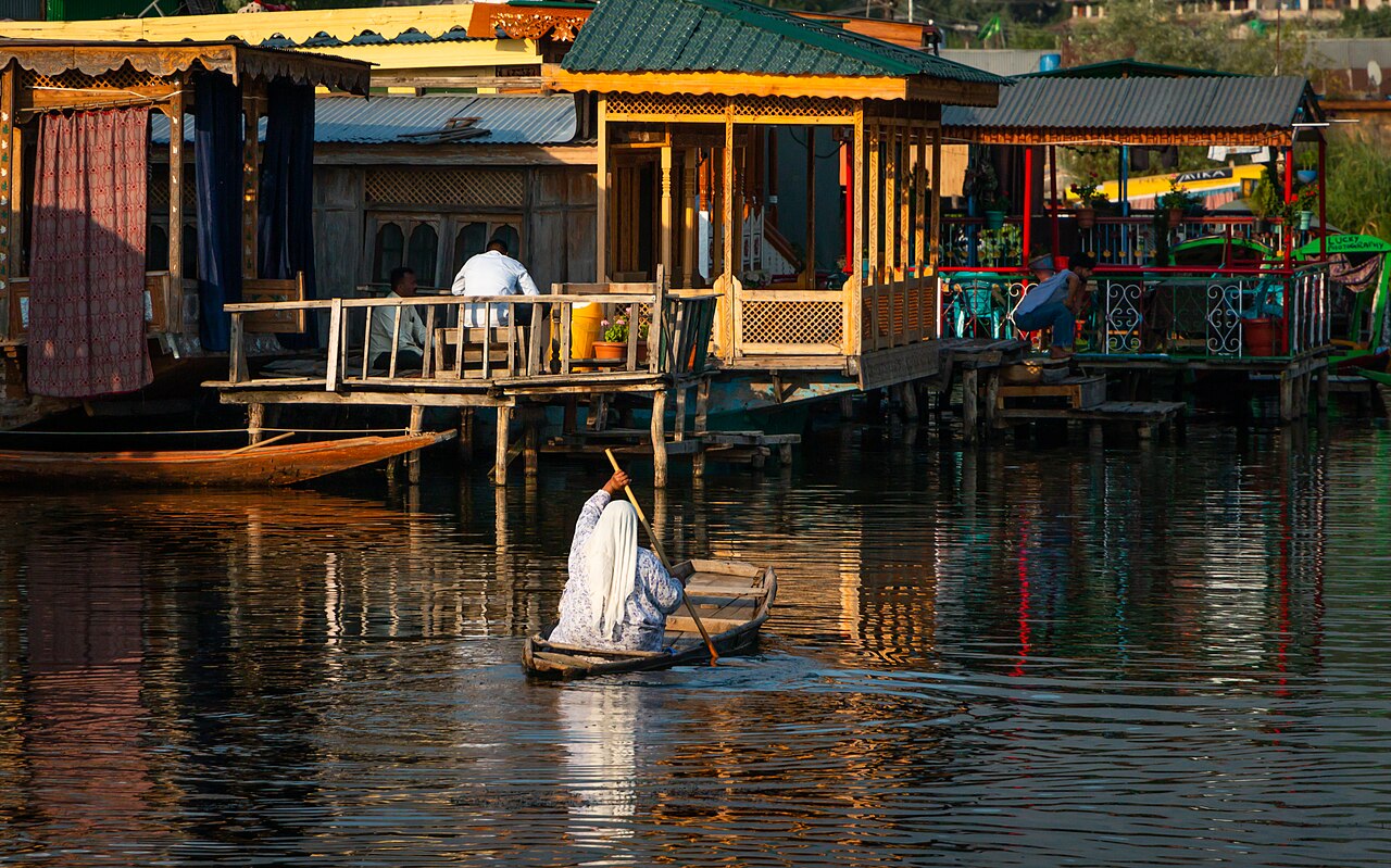 A houseboat and rower on the still water of Dal Lake